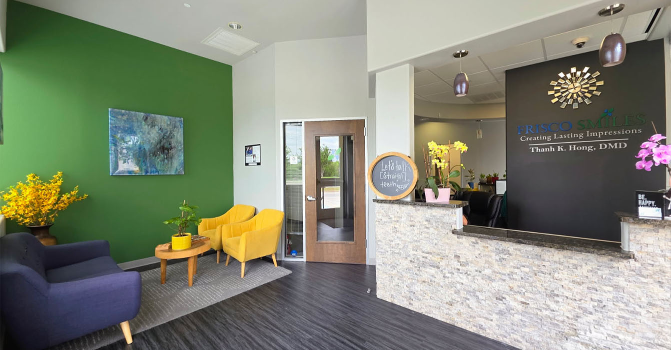 The image shows an interior space with a modern design, featuring green walls, a reception desk with a sign reading  Welcome to Our New Office,  a seating area with chairs, a yellow flower arrangement on the counter, and a framed picture hanging above the desk.