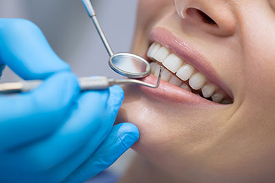 A woman receiving dental care with a dentist s hand holding her mouth open.