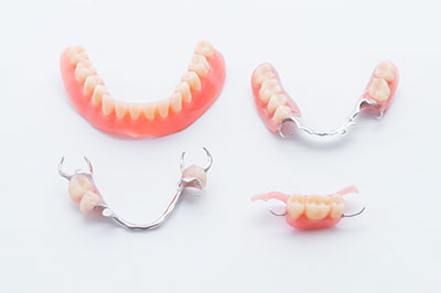 The image shows a collection of dentures with visible teeth, displayed against a white background.