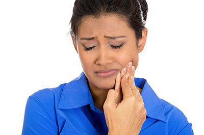 The image shows a woman with her eyes closed, holding her hand to her mouth, possibly expressing pain or discomfort, against a white background.