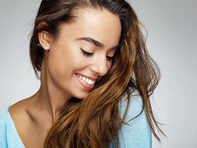The image features a young woman with long hair smiling at the camera, wearing a blue top, with a close-up on one side showing her profile.